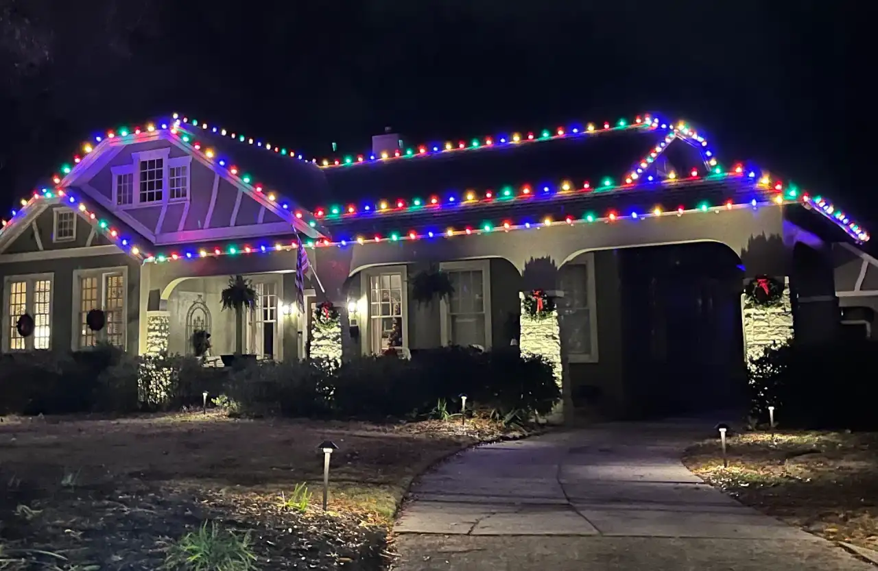 Craftsman-style home with multicolor C9 lights along the roofline and porch at night